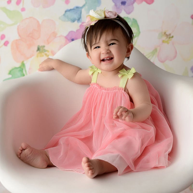 Newborn portrait of a baby in a gray vest and bow tie with a soft smile