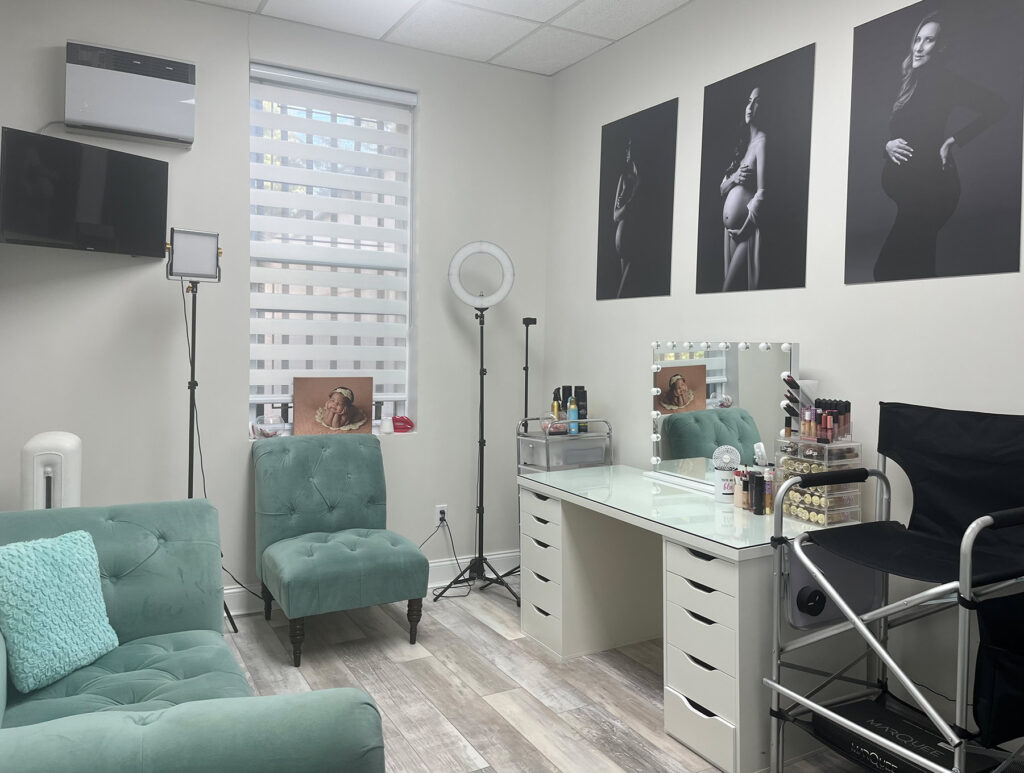 A well-equipped makeup room featuring a chair, desk, and mirror for maternity photography