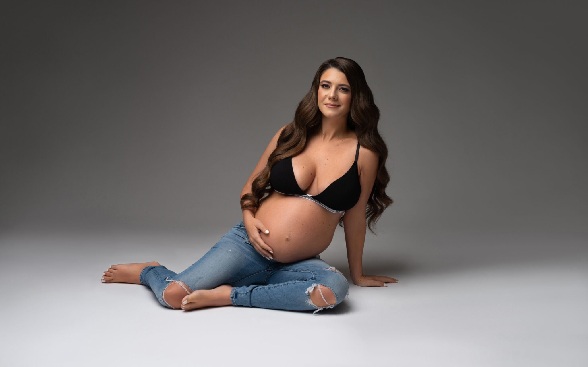 Maternity portrait of woman in jeans on the floor