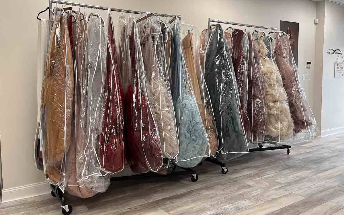 A room with a rack of clothes displaying a variety of dresses in different colors and styles.