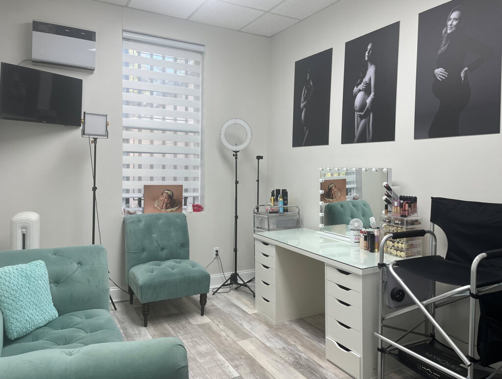 A well-equipped makeup room featuring a chair, desk, and mirror for maternity photography